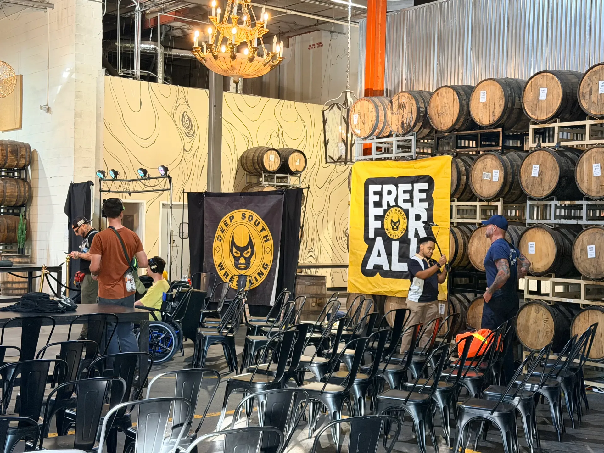 Indoor Deep South Wrestling venue with rows of chairs, barrels, and Free For All banner